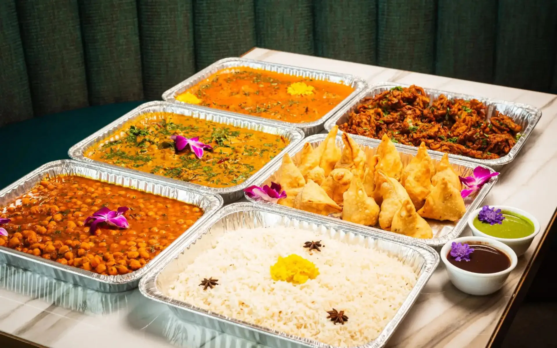 Indian curries, rice and samosas arranged for a shared buffet
