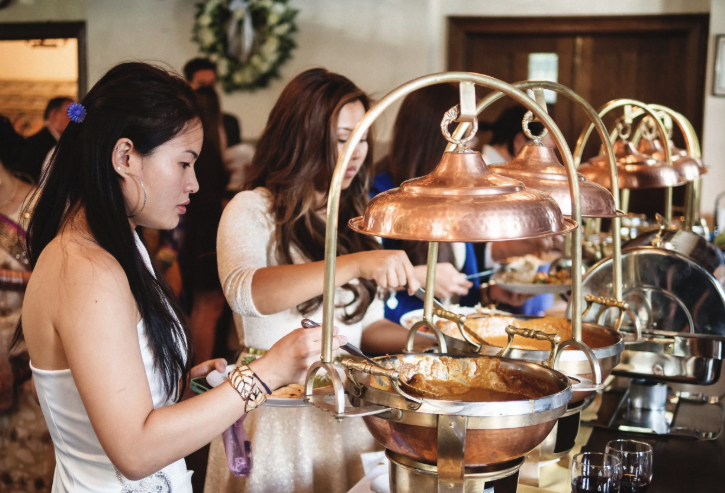 Guests serving themselves from copper buffet warmers at an indoor catered event