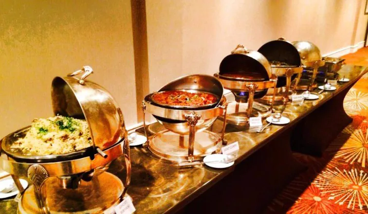 A long buffet line with gold chafers arranged for catered service