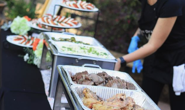 An outdoor buffet table with grilled items and side trays prepared for service