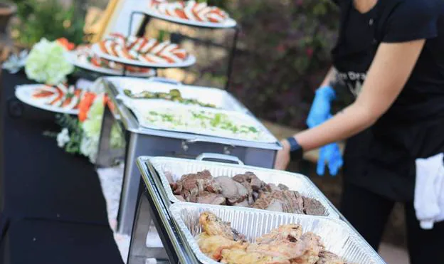 An outdoor buffet table with grilled items and side trays prepared for service